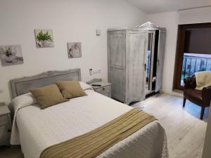 a bedroom with a bed and a chair and a window at A casa dos Pobres in Muxia