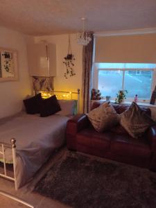 a bedroom with a bed and a couch and a window at Little Dorrit Studio flat Rochester ME1 1XZ in Strood