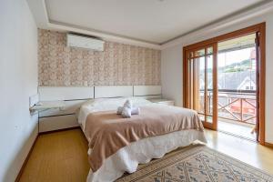 una camera con un letto e una grande finestra di Rosa Edifício Don Carletto a Gramado