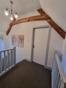 a hallway with a white door and a ceiling at Wassail Barn Wedmore in Wedmore
