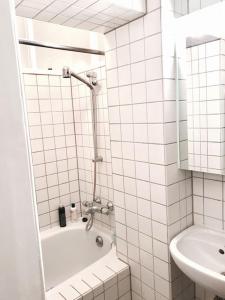 a white tiled bathroom with a tub and a sink at Ground Floor in Villa in Charlottenburg Garden View in Berlin