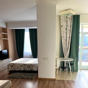 um quarto com uma cama, uma mesa e uma janela em Stefan cel Mare 1 studio em Chisinau