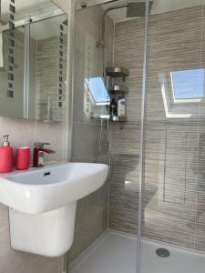 ein Badezimmer mit einem weißen Waschbecken und einer Dusche in der Unterkunft Paradigm House, Modern 2-Bedroom Duplex Apartment 2, Free Parking, Oxford in Oxford