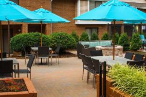 un patio avec des tables et des chaises et des parasols bleus dans l'établissement Tysons Corner Suites, A Baymont by Wyndham, à Vienna