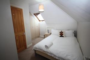 een slaapkamer met een bed met witte lakens en kussens bij Oaks House in Hanworth