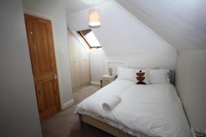 a bedroom with a bed with white sheets and pillows at Oaks House in Hanworth