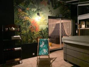a chair in a room with a mural of plants at Maison avec jacuzzi proche Rennes jardin calme in Noyal-Châtillon-sur-Seich