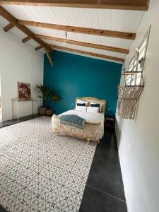 a bedroom with a bed and a blue wall at Le Poppy Palm in Sainte-Luce