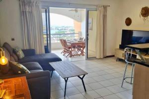 a living room with a couch and a tv and a table at Appartement Hana Iti breathtaking on the ocean at the entrance of Papeete in Papeete