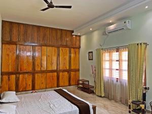 1 dormitorio con 1 cama con paredes de madera y techo en Monappa Estate - Beautiful Riverside Farm house in Udupi, en Udupi