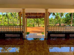 Casa grande con un gran porche delantero con palmeras. en Monappa Estate - Beautiful Riverside Farm house in Udupi, en Udupi