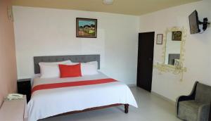 1 dormitorio con cama con almohada roja y silla en Hotel Jardines Del Carmen, en San Cristóbal de Las Casas