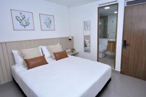 1 dormitorio con 1 cama blanca grande y baño en Reset (Hotel-Cafe-Coworking) en Cali