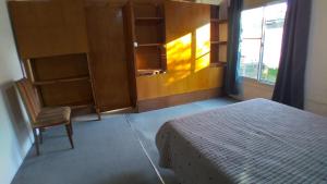 1 dormitorio con 1 cama, 1 silla y 1 ventana en Dto por día en Tandil en Tandil