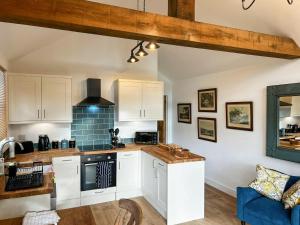 a kitchen with white cabinets and a blue couch at South Downs Lodge in Droxford