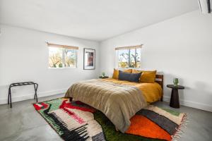 a bedroom with a bed and a rug and two windows at Wonder Valley Green House - Near Joshua Tree National Park in Twentynine Palms