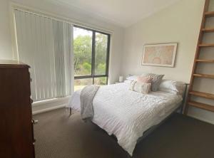 a bedroom with a bed and a large window at Bawley Point accommodation in Bawley Point
