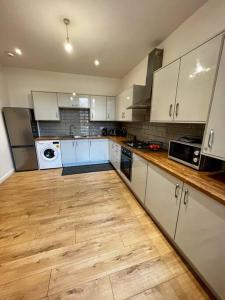 a kitchen with white cabinets and a wooden floor at Luxury Apartment in Nuneaton in Nuneaton