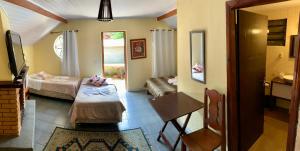 um quarto com duas camas e uma mesa num quarto em Pousada Chalana em Monte Verde