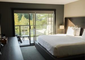 1 dormitorio con 1 cama y puerta corredera de cristal en Tofino Resort + Marina, en Tofino