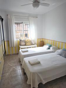 a bedroom with three beds and a window at Casa en el Centro de Cabo de Palos Cerca a Clubes de Buceo in Cabo de Palos