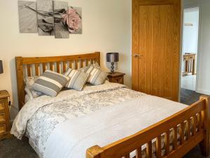 Un dormitorio con una gran cama de madera con almohadas en Four Burrows Bungalow, en Chacewater