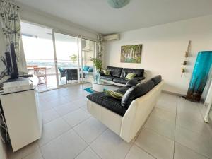 un soggiorno con un divano e una televisione di Appartement de standing vue mer a Schœlcher