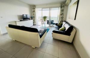 a living room with two couches and a window at Appartement de standing vue mer in Schœlcher