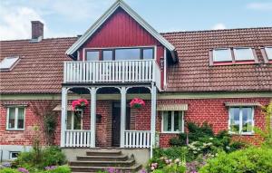 une maison en briques rouges avec une véranda blanche et des fleurs roses dans l'établissement Lovely Home In Hssleholm With Wifi, à Tjörnarp