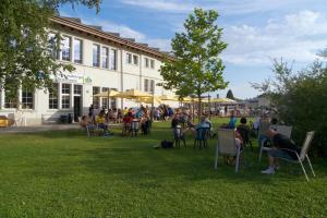 eine Gruppe von Personen, die vor einem Gebäude auf Stühlen sitzen in der Unterkunft Swiss Hostel Lago Lodge in Biel