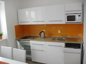 a kitchen with white cabinets and a sink and a microwave at Apartmán Linda in Lipno nad Vltavou
