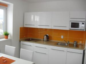 a kitchen with white cabinets and a sink at Apartmán Linda in Lipno nad Vltavou