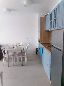 索佐波爾的住宿－Апартамент в Green Life Beach Resort Sozopol，一间带桌子的厨房和一间带蓝色橱柜的厨房