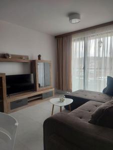 - un salon avec un canapé, une télévision et une table dans l'établissement Апартамент в Green Life Beach Resort Sozopol, à Sozopol