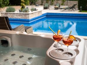 two cocktails sitting on a table next to a swimming pool at Füge Villa Luxury & Wellness in Balatonfüred