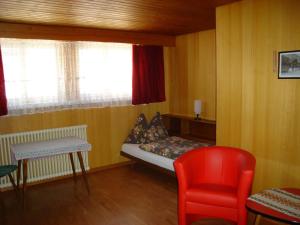 een kleine kamer met een bed en een rode stoel bij Hotel Milan B&B in Ringgenberg
