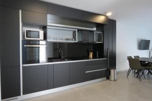a kitchen with black cabinets and a sink and microwave at Villa Omazic in Trogir