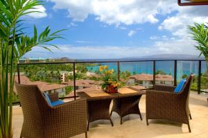 a patio with a table and chairs and a view of the ocean at Wailea Beach Villas in Wailea