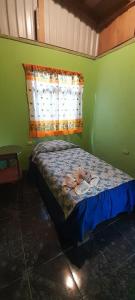 a small bedroom with a bed in a green wall at La casa de tia in Monteverde Costa Rica