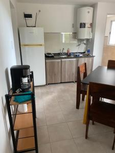 a kitchen with a table and a white refrigerator at Parque jardín in La Falda