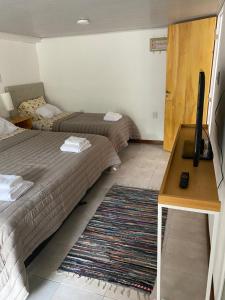 a hotel room with two beds and a desk and a rug at Parque jardín in La Falda