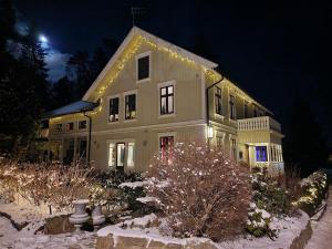Una casa grande con luces de Navidad encendidas por la noche en Det Gamle Meieriet en Vidnes