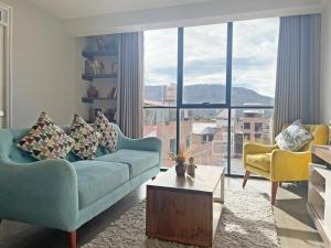 a living room with a blue couch and a large window at Town Center Apartments in Urubamba