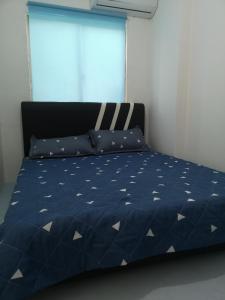 a bed with a blue comforter and a window at SPOT ON 90735 night Stayin in Sibu