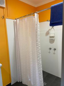 a shower with a white shower curtain in a bathroom at Beachcomber Caravan Park in Mallacoota