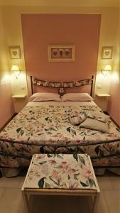 ein Schlafzimmer mit einem Bett mit geblümter Tagesdecke in der Unterkunft La casina dei cuori di nonna Miglia in Pallerone