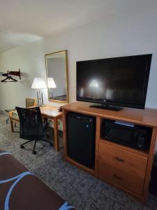 a hotel room with a large television and a desk at SureStay Plus Hotel by Best Western Grand Island in Grand Island