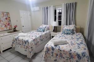 a bedroom with two beds and a mirror at Chalet Cassie in Montego Bay