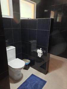 a bathroom with a toilet and a black tiled wall at Pousada Do Moinho in Nazaré Paulista