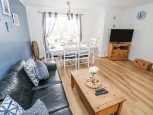 uma sala de estar com um sofá de couro preto e uma mesa em Driftwood House em Saundersfoot